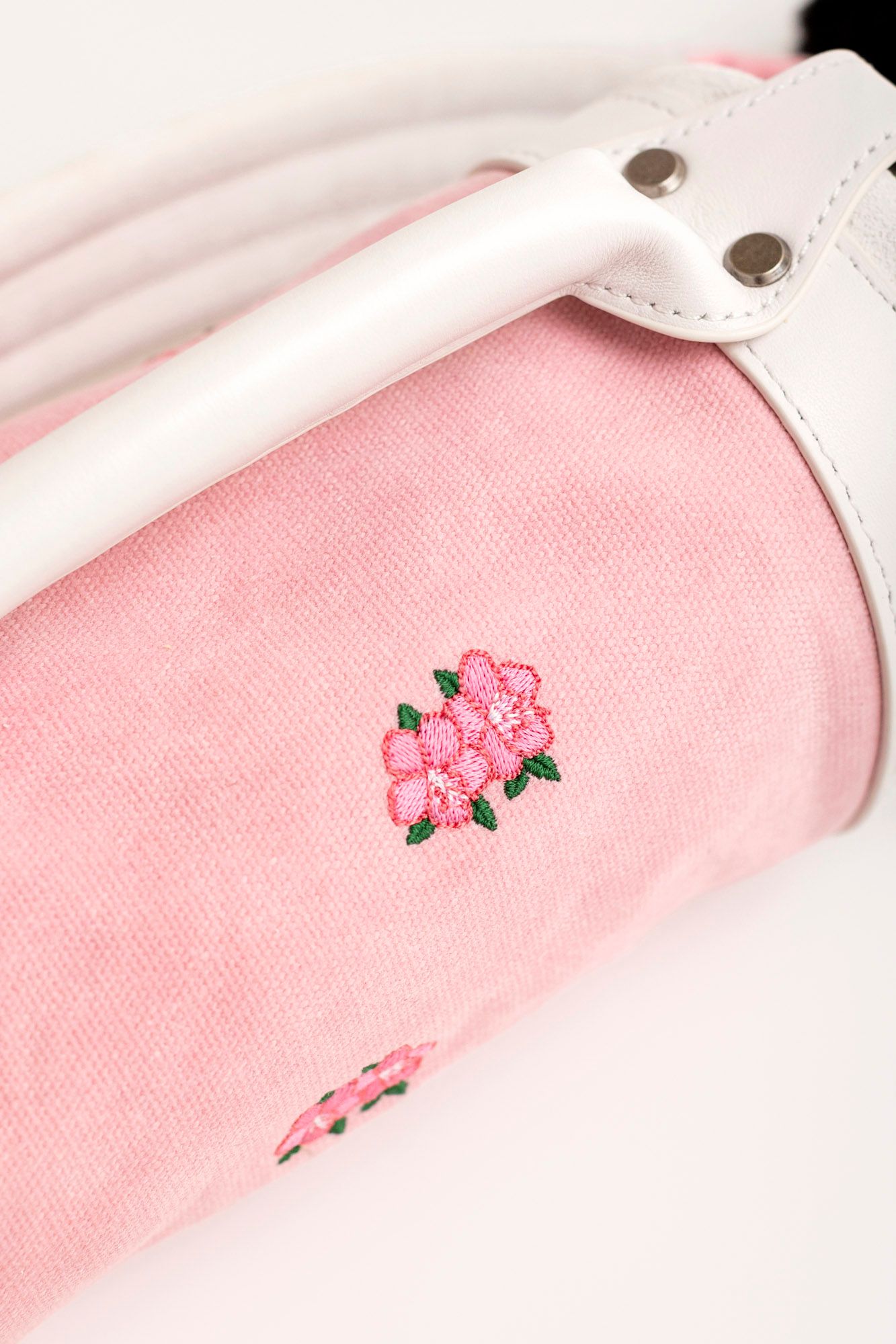 Close-up view of delicate pink floral embroidery on white fabric with lace trim detail.