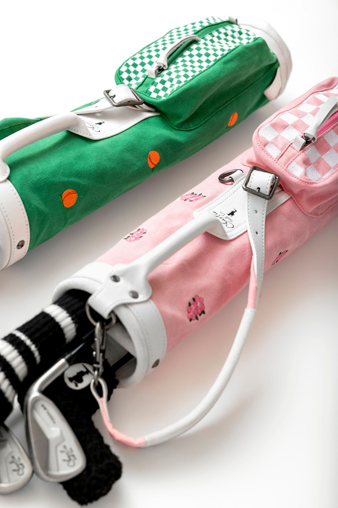 A line of colorful golf club head covers in pink and green with checkered patterns and animal designs.