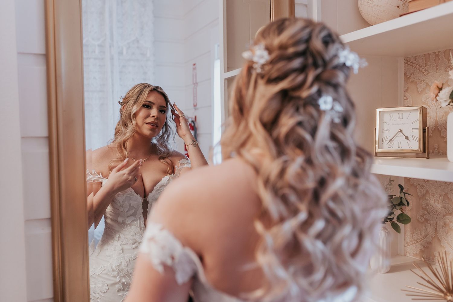 Bride in white lace gown getting ready in elegant room with vintage decor and soft natural lighting.