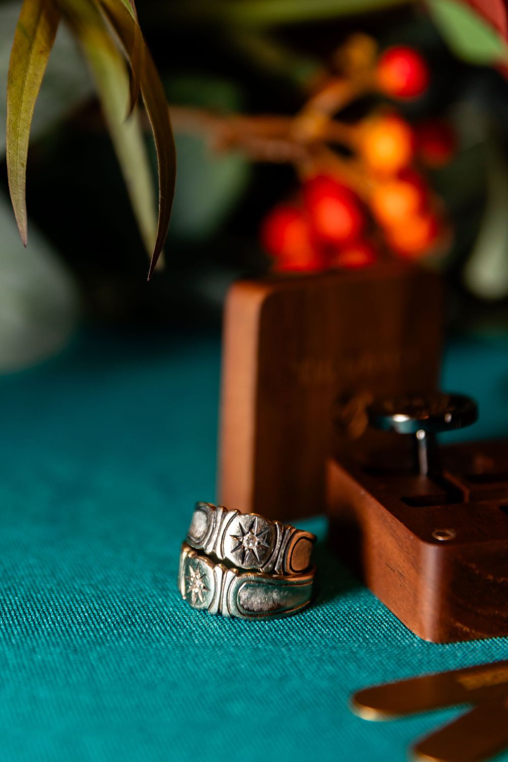 Vintage silver rings with star and moon engravings displayed on teal surface with wooden box.