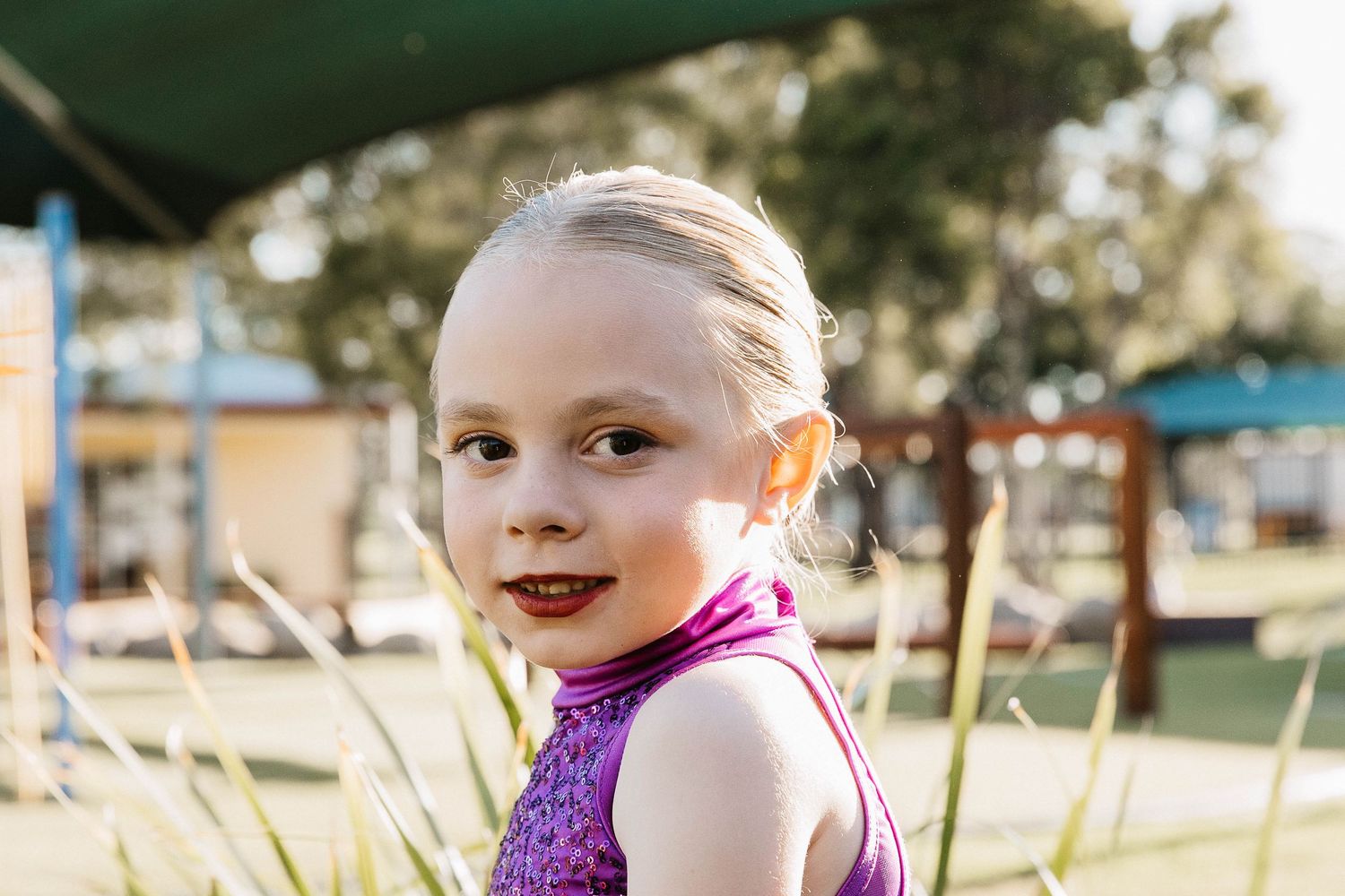 Little girl looking sitting in the playground during a dance costume photo shoot.