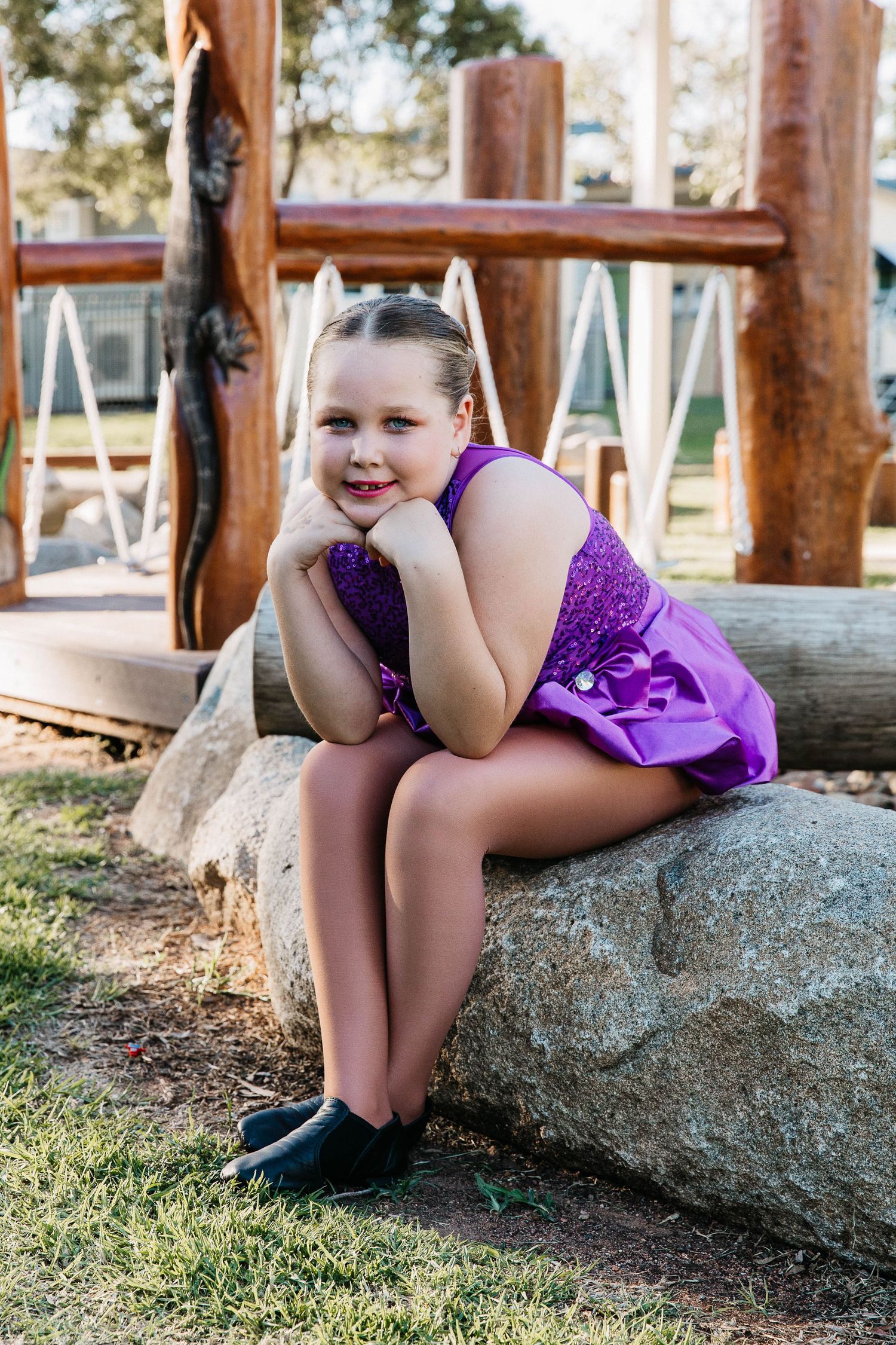 Little girl sitting on a rock in a creek during a dance costume photo shoot.