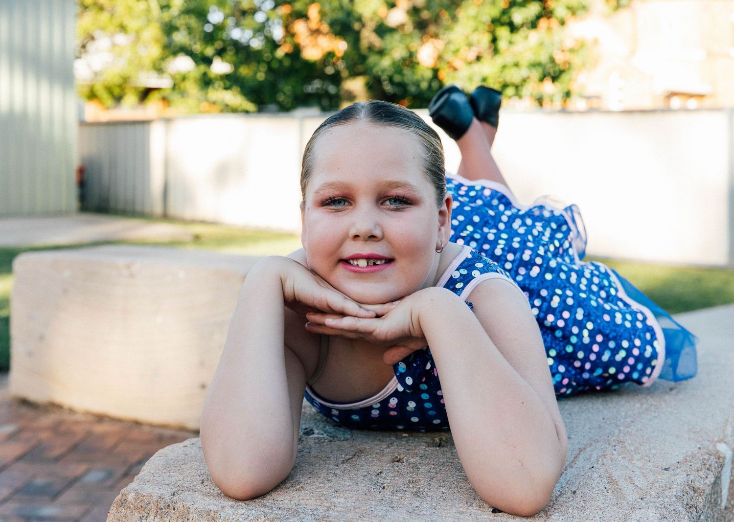 Little girl laying on a sandstone rock during a dance costume photo shoot.