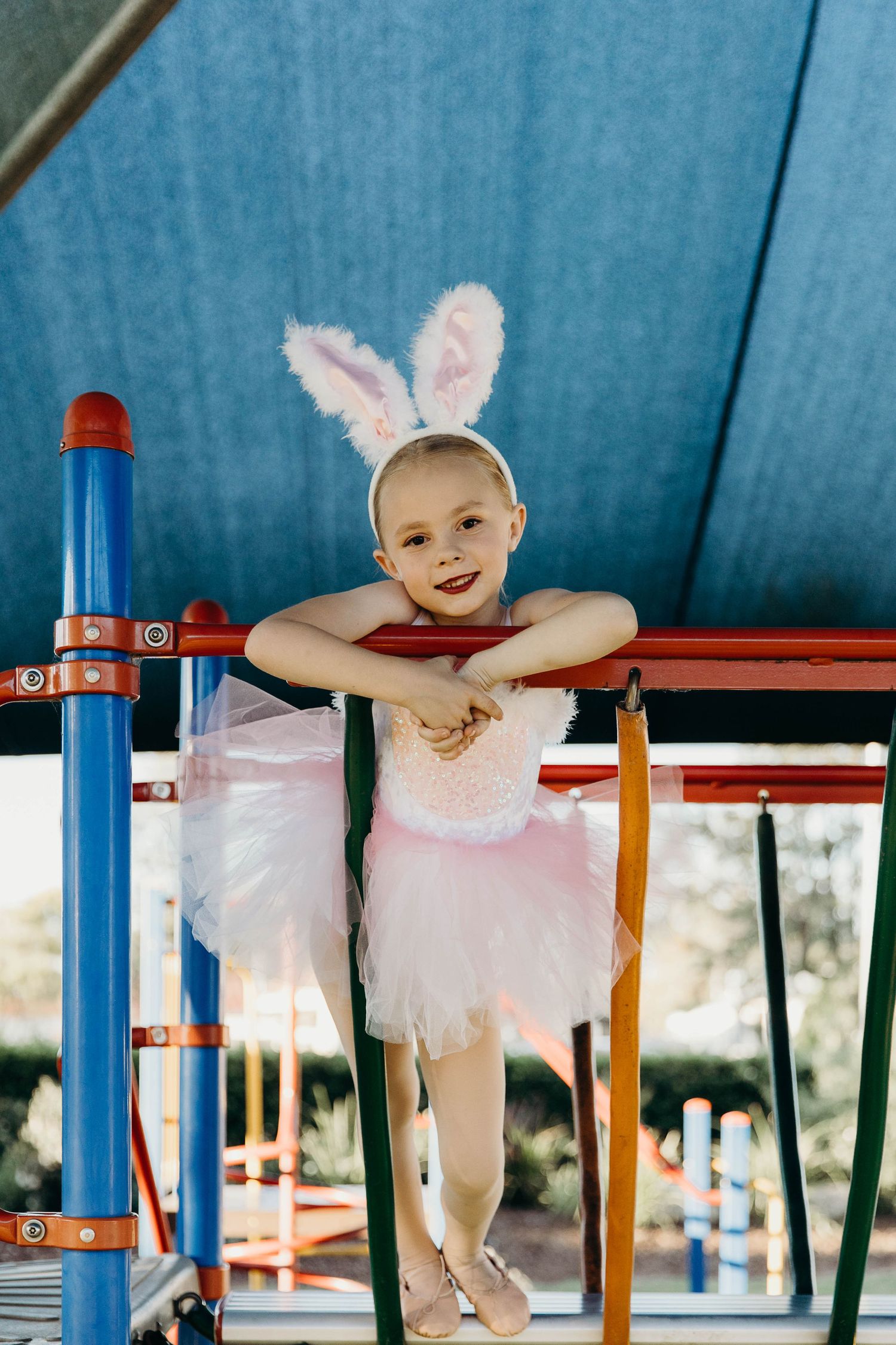 Little girl looking and leaning over the playground during a dance costume photo shoot.