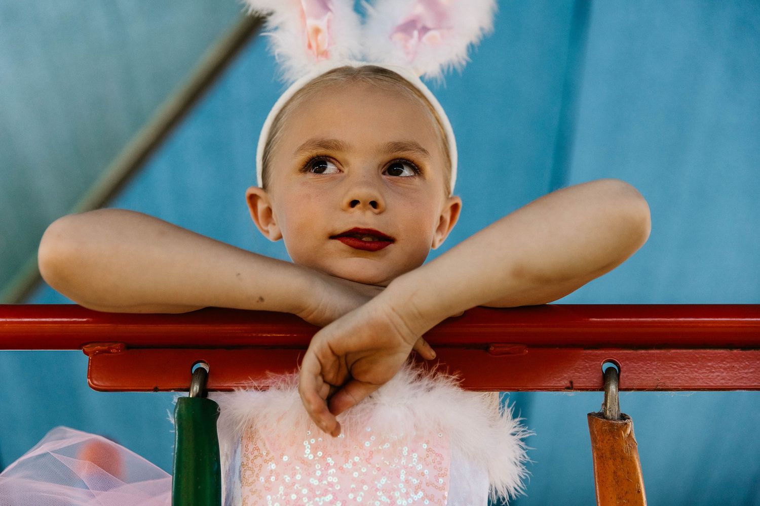 Little girl looking and leaning over the playground during a dance costume photo shoot.