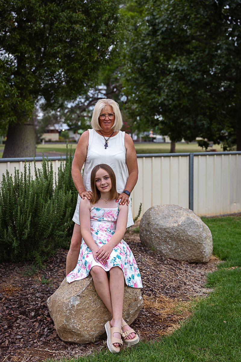 girl and grandmother sitting on rocks in playground