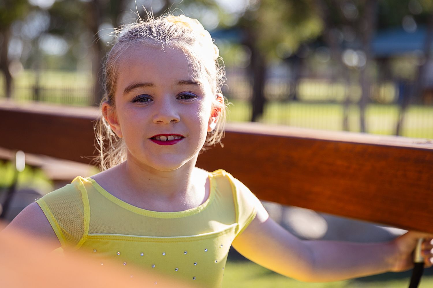 Little girl looking and leaning over the playground during a dance costume photo shoot.