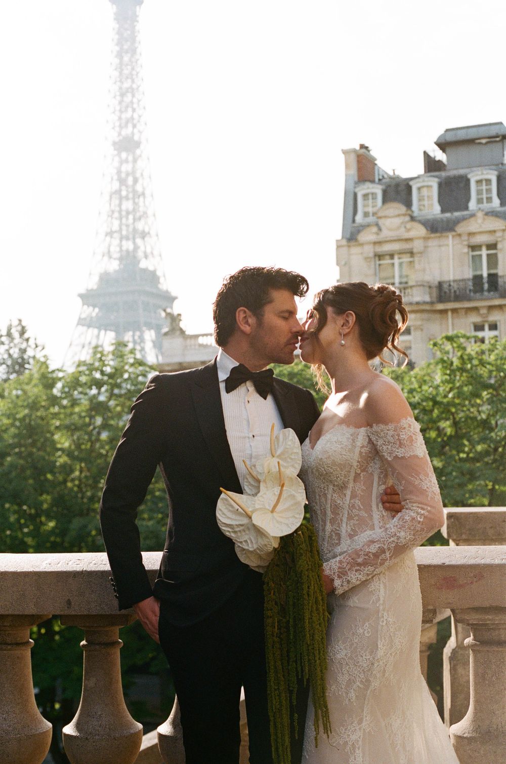 Couple sharing a romantic kiss in wedding attire with the Eiffel Tower in the background in Paris.