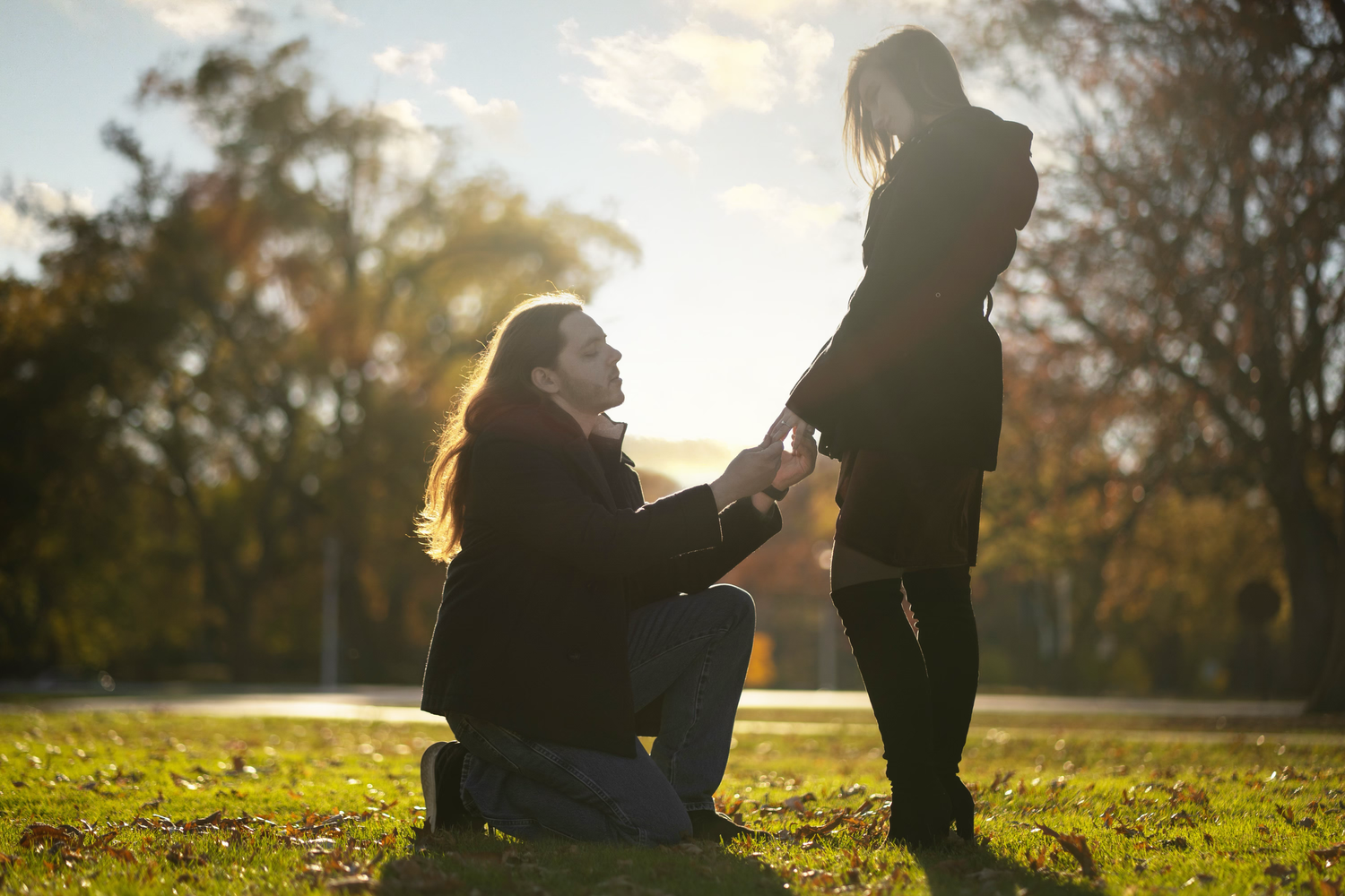 Silhouetted figures stand together in a grassy field during golden hour sunlight.
