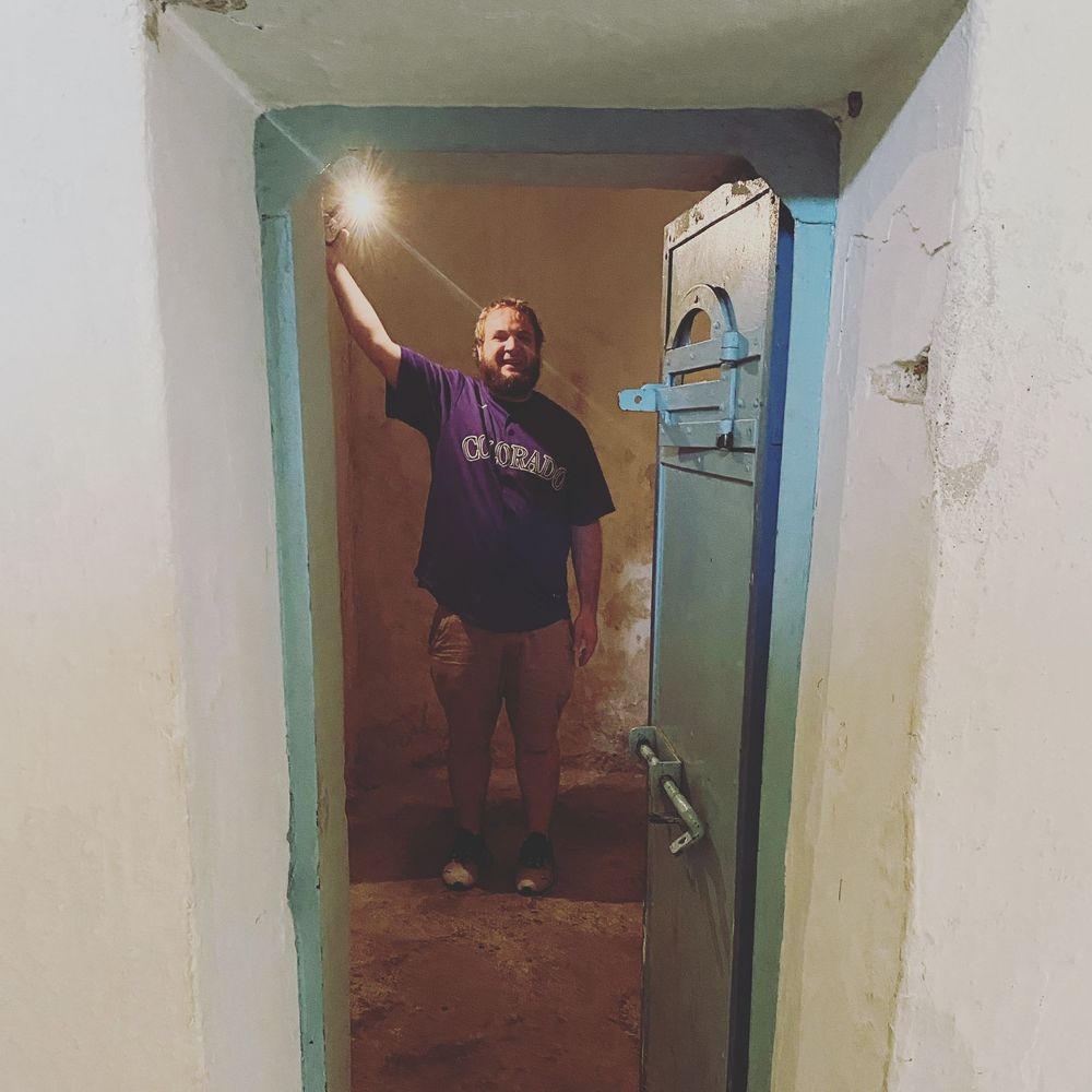 Someone holding a sparkler stands in a doorway with turquoise trim in a dimly lit hallway.