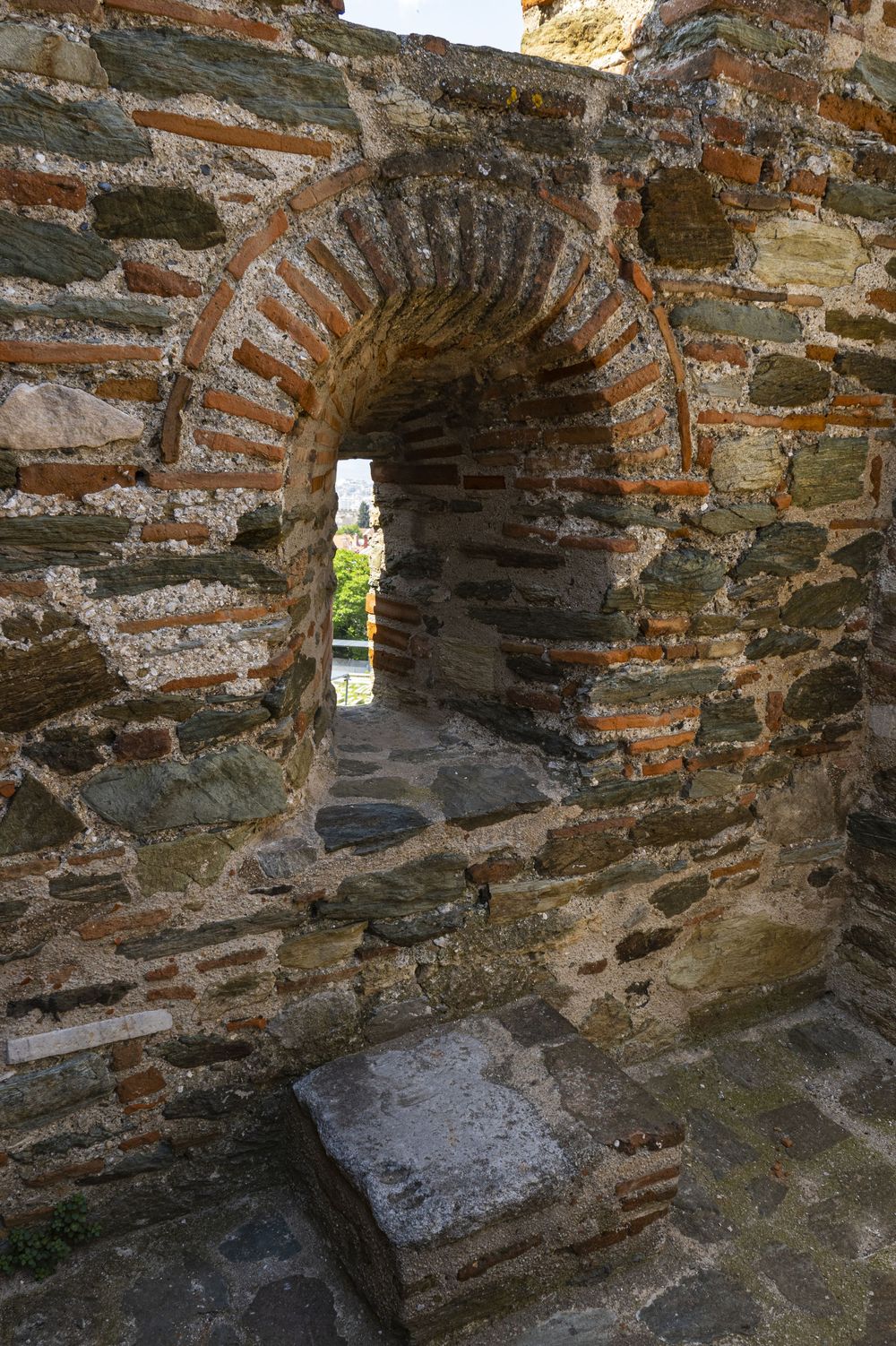 Ancient stone wall with arched window openings shows detailed brick and mortar construction in a historic ruin.
