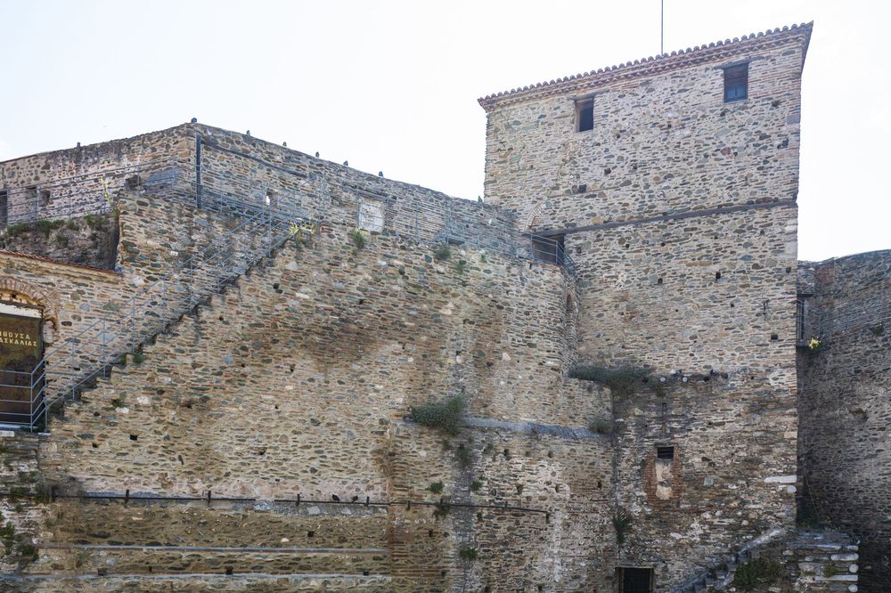 Ancient stone fortress walls and tower with weathered stairs along the exterior of a historic medieval structure.