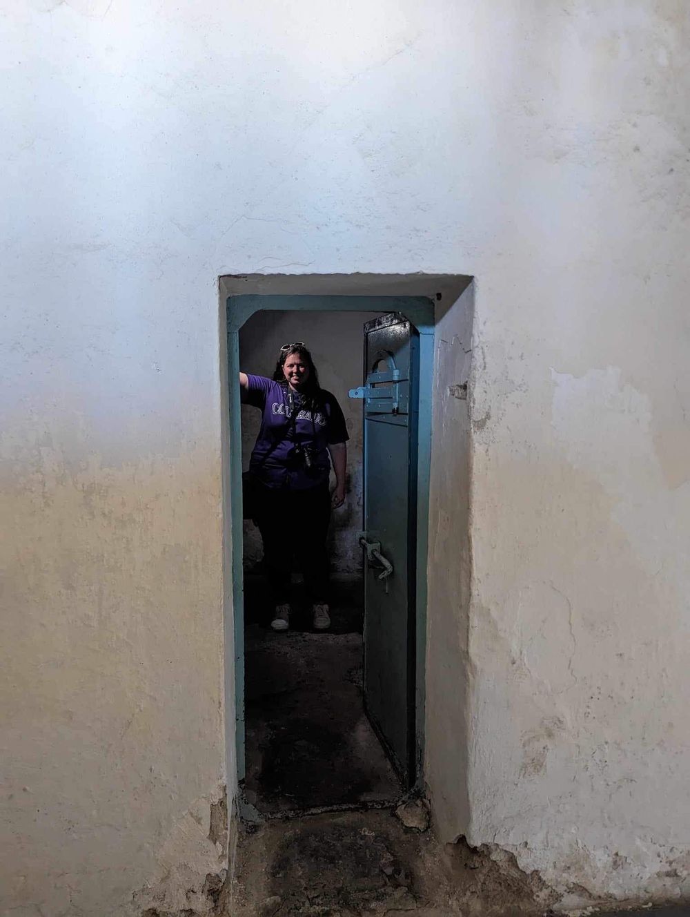 A sequence of four photos showing a person entering through a dark doorway in an old white wall.