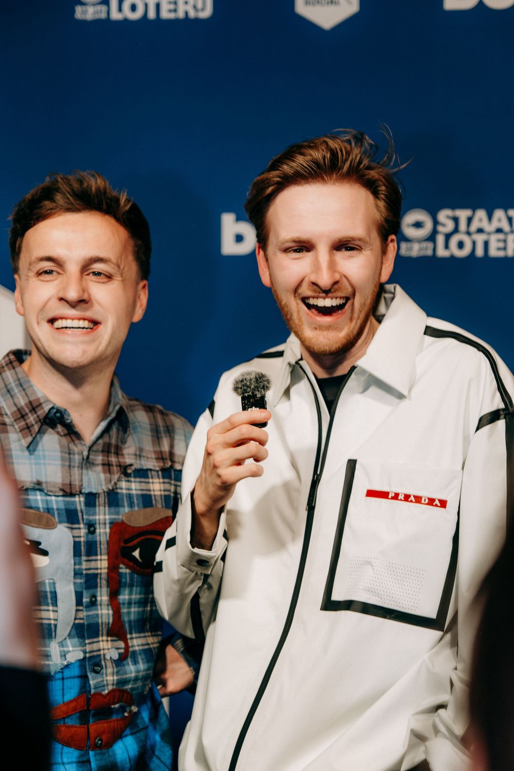 Two smiling men holding microphone posing in front of Staatsloterij and bol.com branded backdrop.