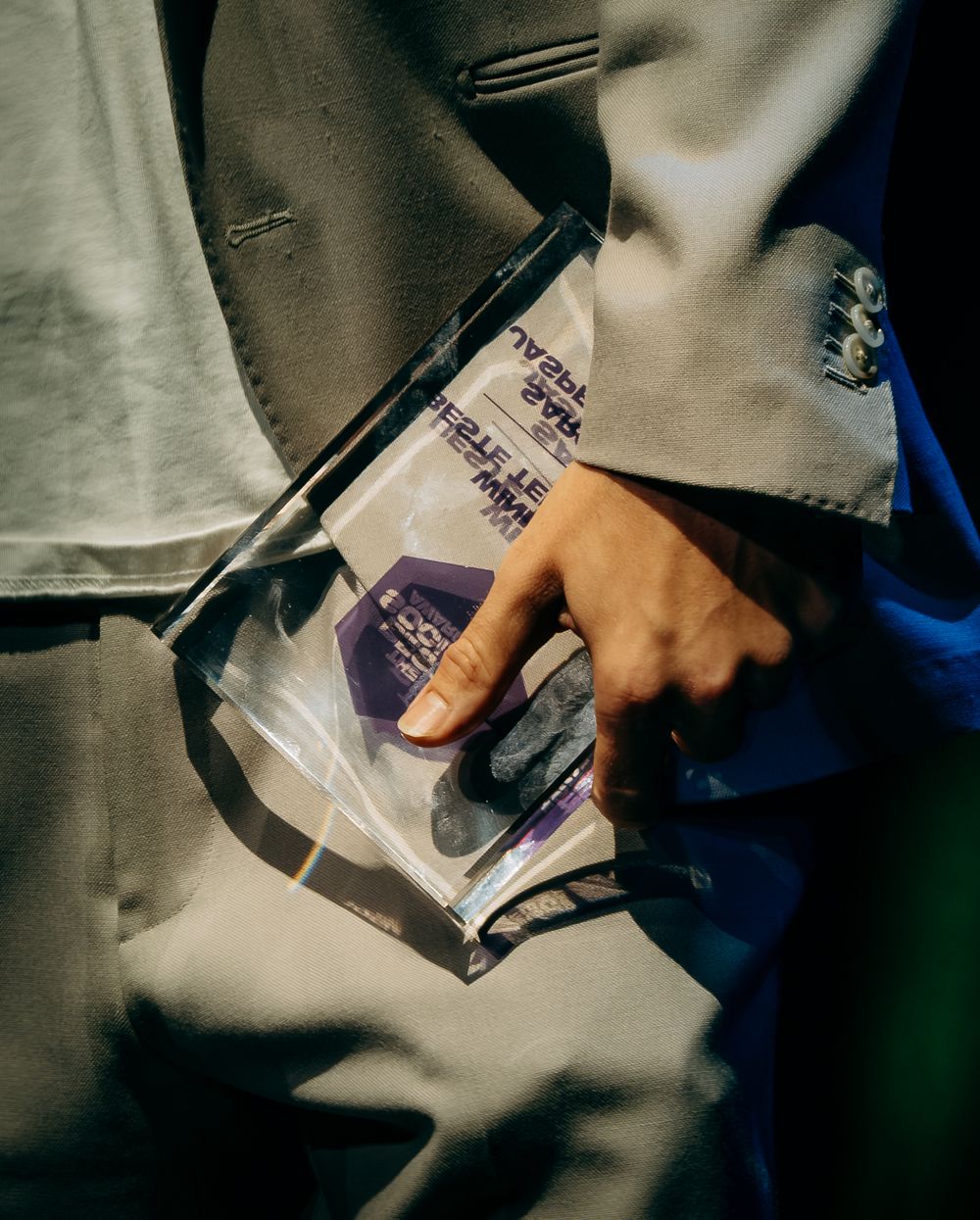 Close-up of a hand holding a clear bag with award materials at a formal event.