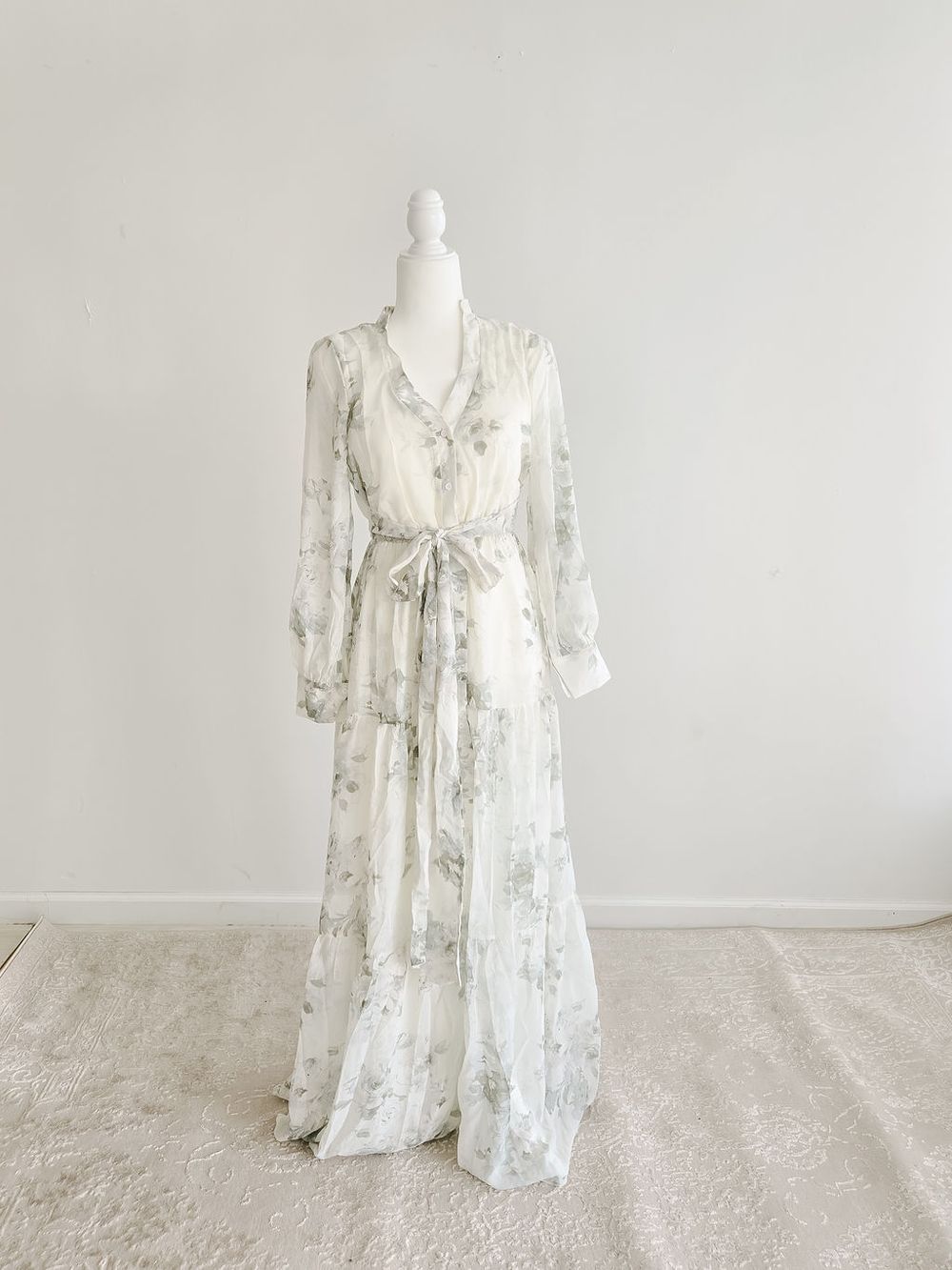 Romantic white floral wrap dress with tie waist and flutter sleeves shown on dress form.
