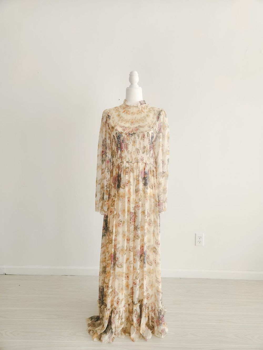 Romantic floral maxi dress with long sleeves and high neckline in soft beige and pink tones.