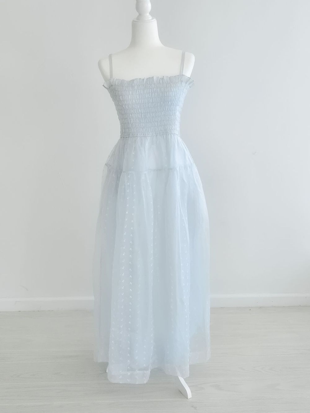 Light blue babydoll sundress with spaghetti straps and smocked bodice displayed on mannequin.