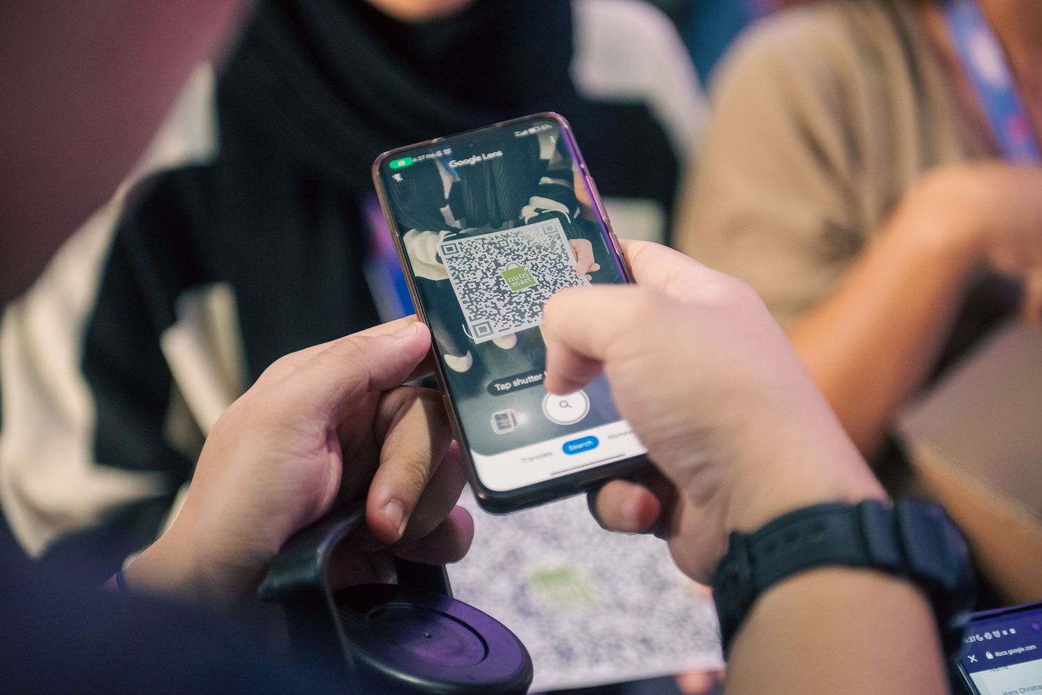 Person holding smartphone displaying a map navigation app with location pins at an indoor event.