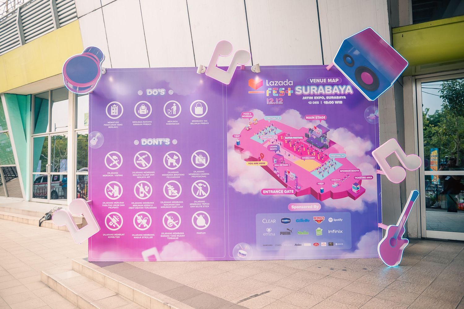 Colorful Lazada Fest Surabaya event signage displaying dos and don'ts rules with vibrant pink and purple festival artwork.