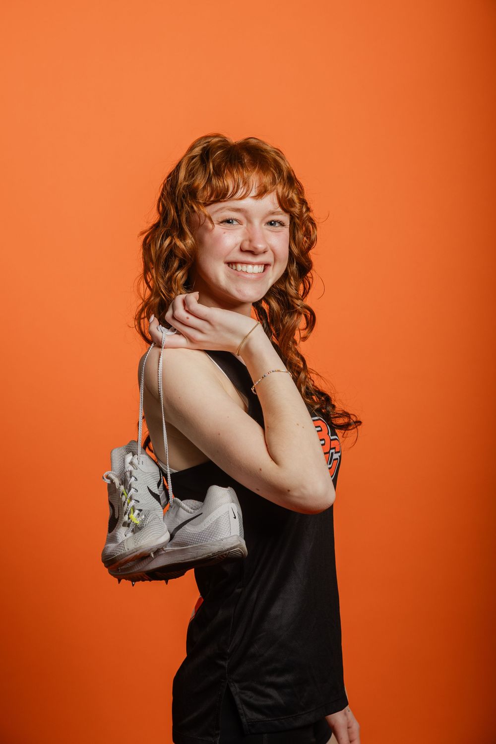 A person in a black top poses playfully against an orange background in a series of connected photos.