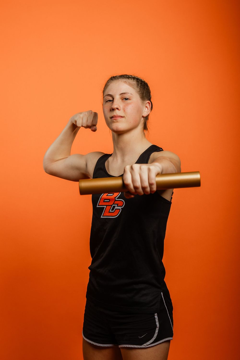 Athletic figure in black tank top poses in sequence against vibrant orange background showing progressive arm movements.