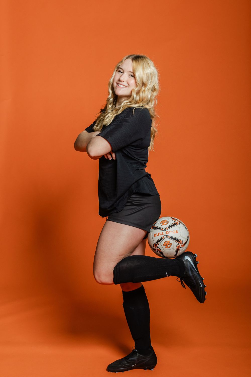 Athletic figure in black uniform poses with soccer ball against vibrant orange background in dynamic sequence.