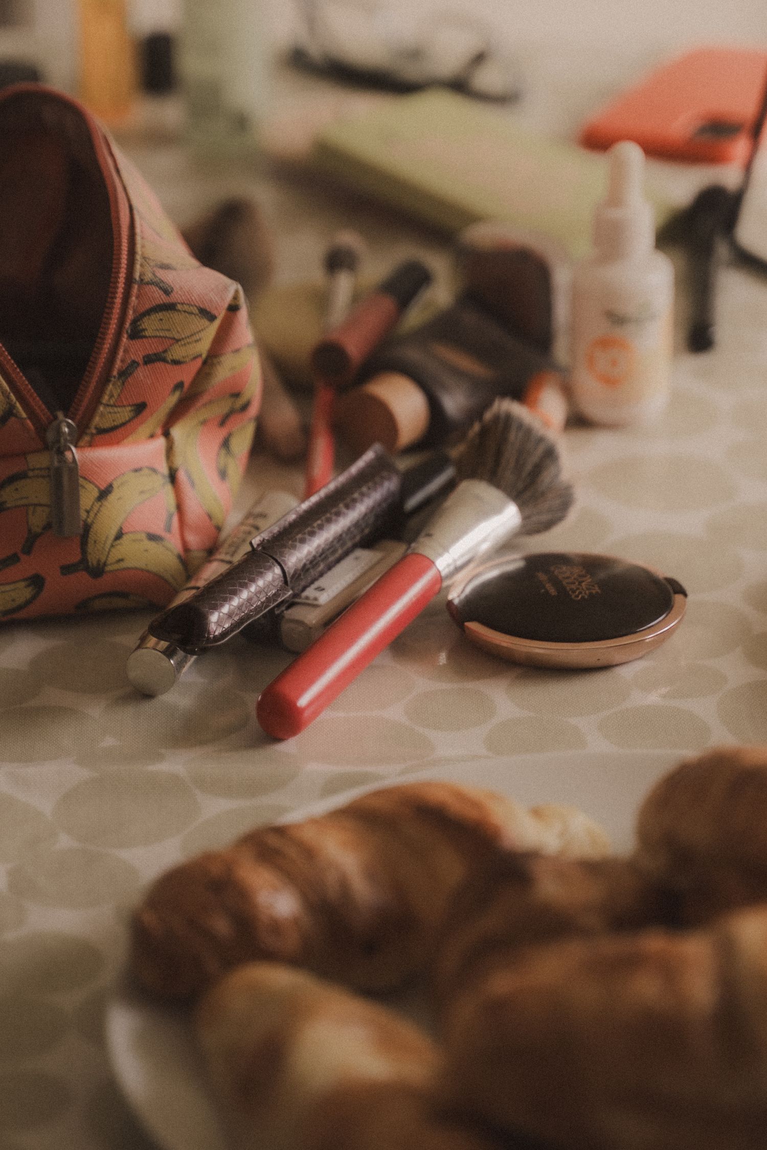 An assortment of makeup products, including lipstick, brushes, and a cosmetic bag, are displayed on a surface.