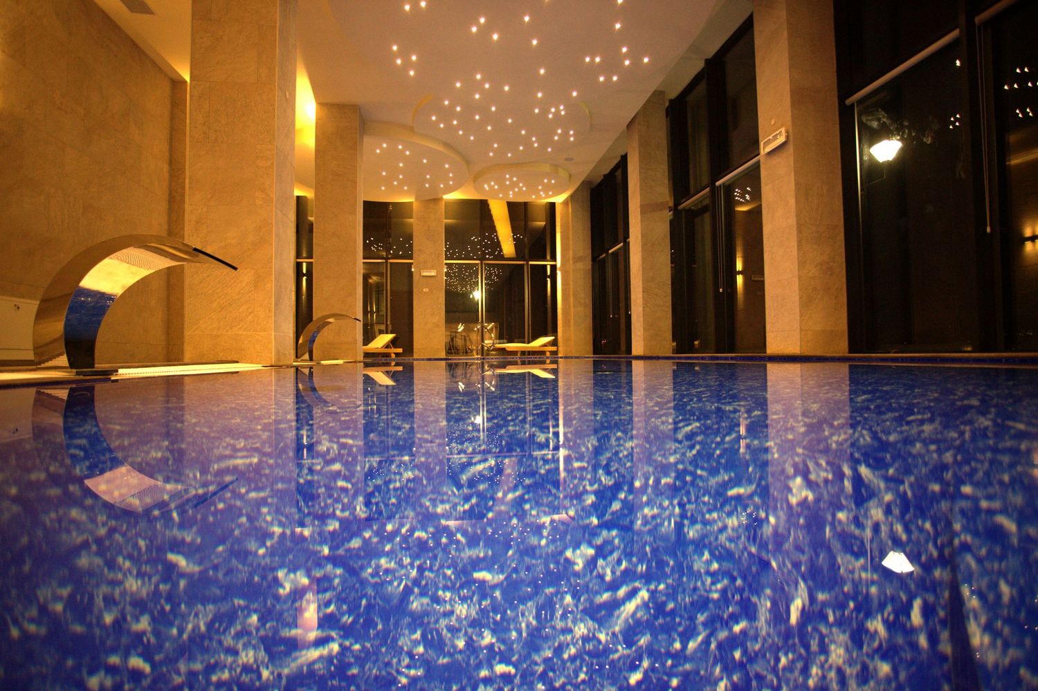 Glowing blue lights illuminate a modern architectural space with glass panels and columns creating a futuristic atmosphere.