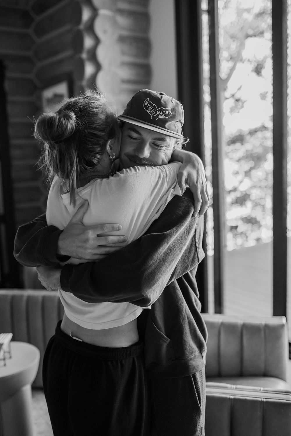 Black and white photo of two dancers embracing during a rehearsal in a sunlit dance studio.
