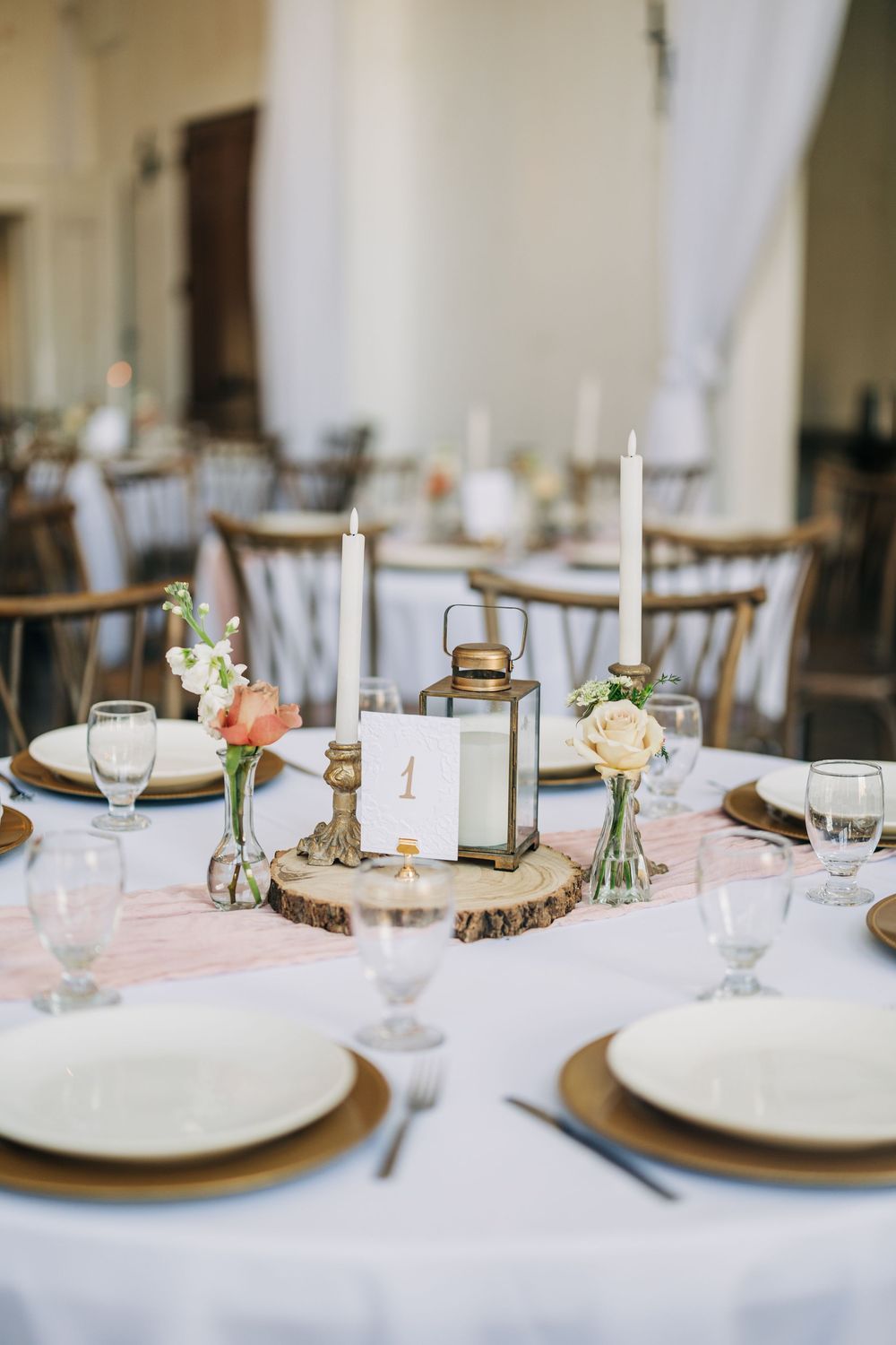 Elegant wedding reception table settings with pink linens, gold charger plates, and delicate floral centerpieces.