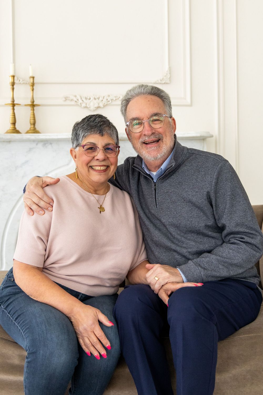 Senior couple sitting close together on couch sharing loving moments in bright living room.