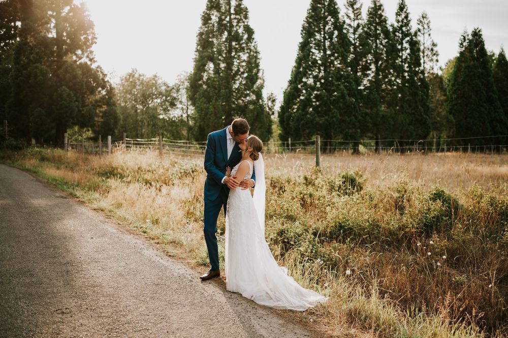 Wedding photography of couple by Williams Beach, in front of golden field in parking lot  kissing during golden hour