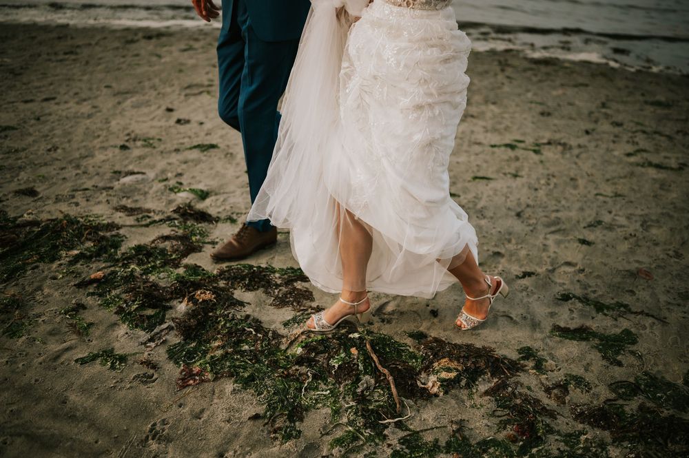 Wedding photography of couple on Williams Beach, groom and bride detail of shoes walking on sand with seaweed