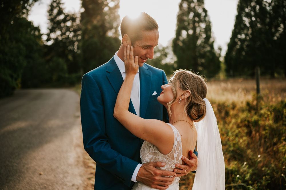 Wedding photography of couple by Williams Beach, in front of golden field in parking lot smiling at each other during golden hour