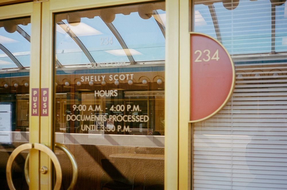 A modern cafe storefront with large windows, glass doors, and a sleek exterior design displaying business hours.