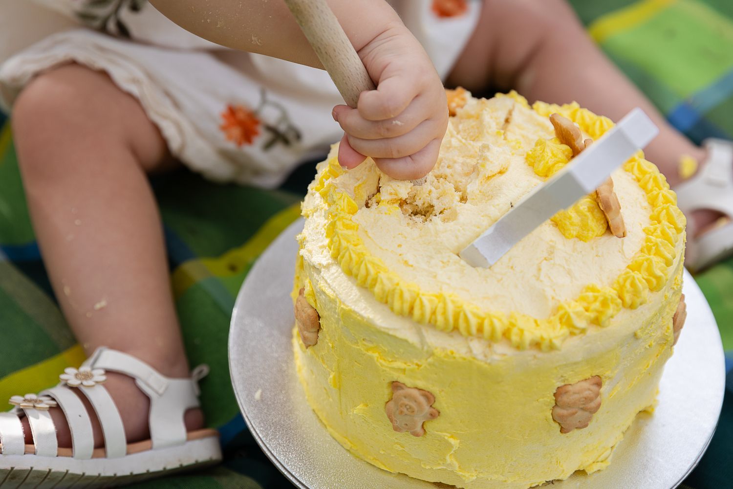 Girl getting messy with cake at teddy bear's picnic cake smash professional photo shoot