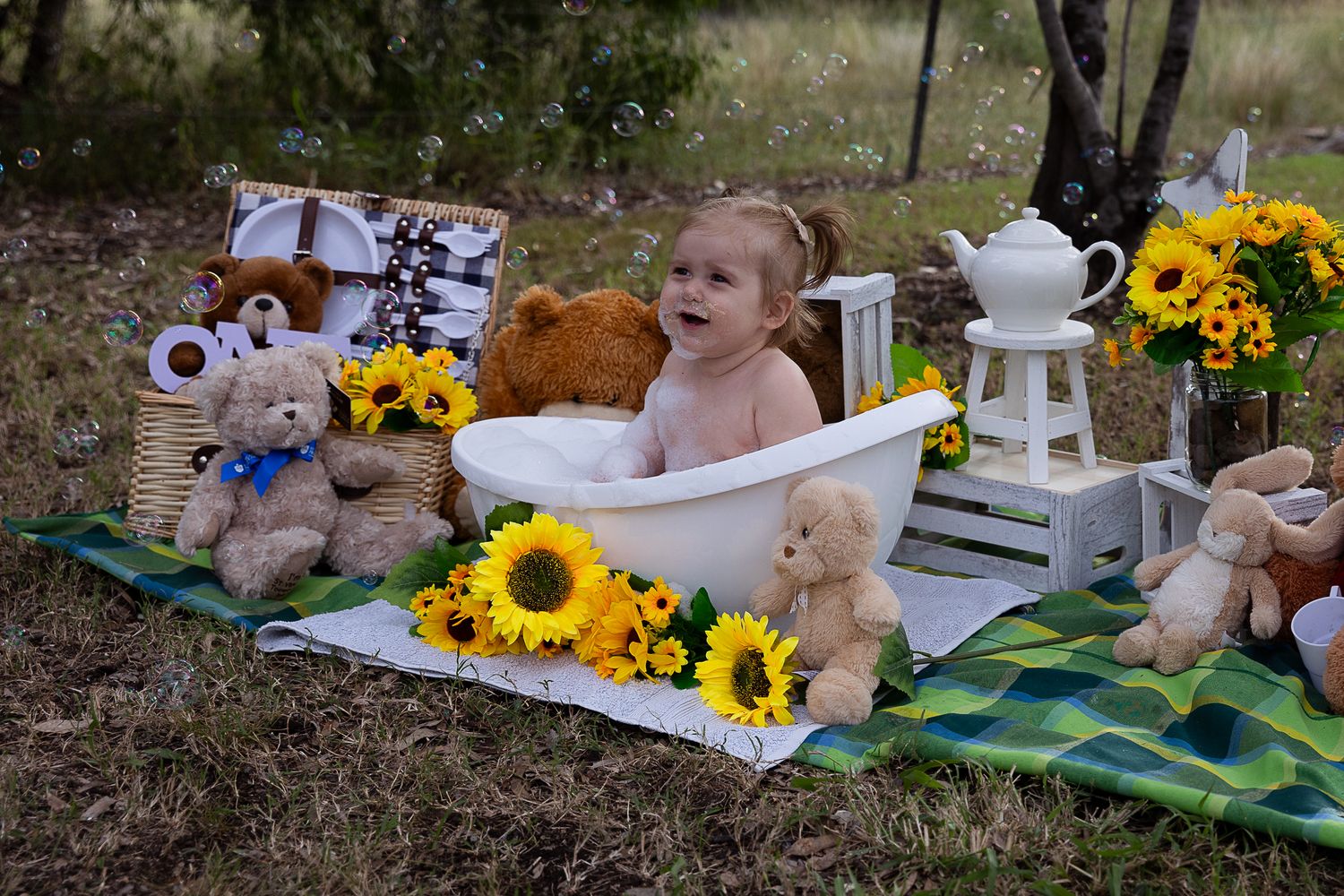 Girl sitting in bubble bath at teddy bear's picnic cake smash professional photo shoot