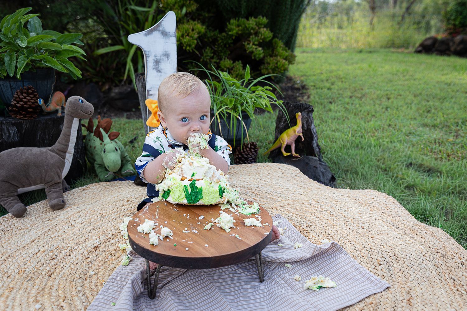 Baby boy eating cake at dinosaur cake smash professional photo shoot