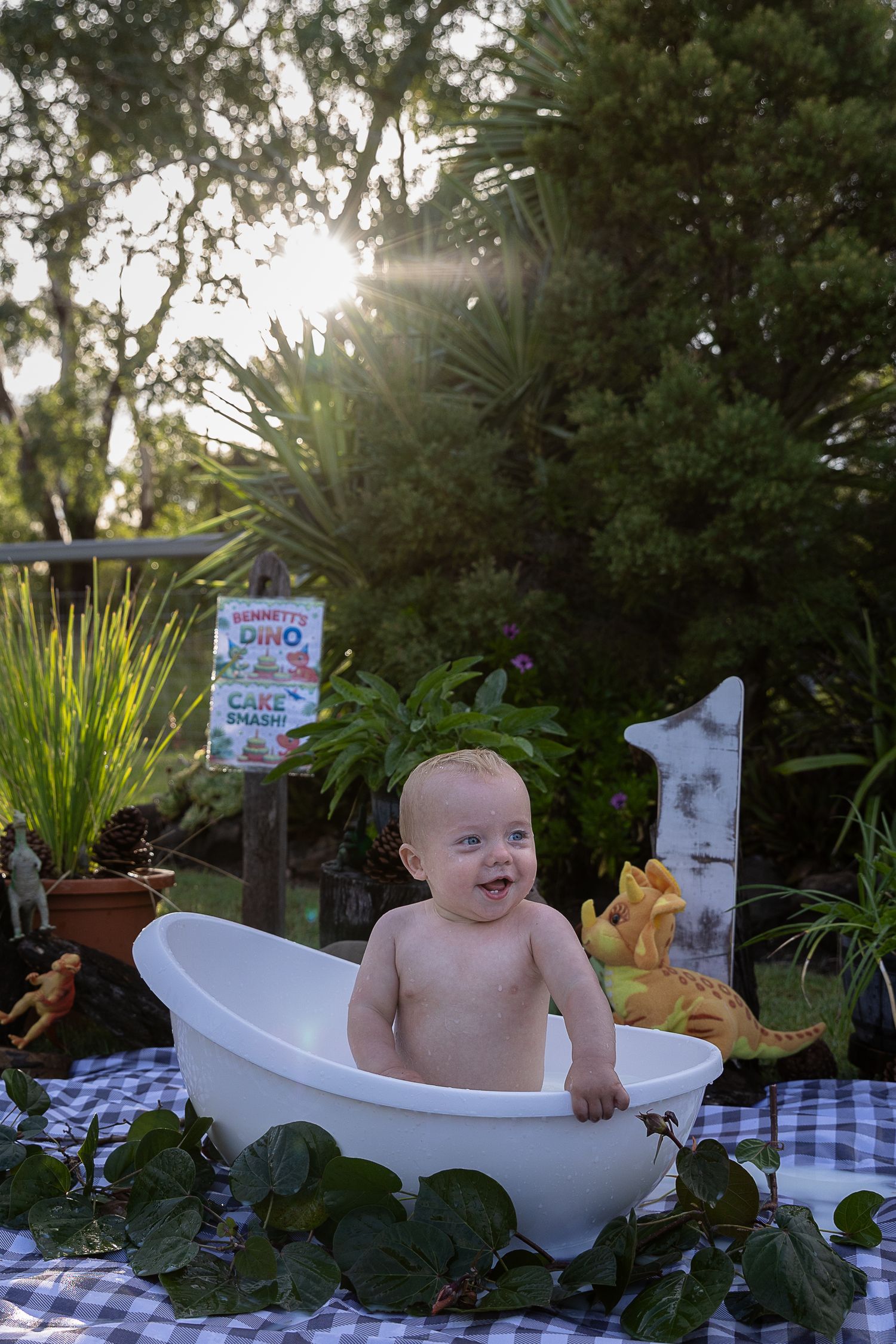 Boy in milk bath at sunset during dinosaur cake smash professional photo shoot