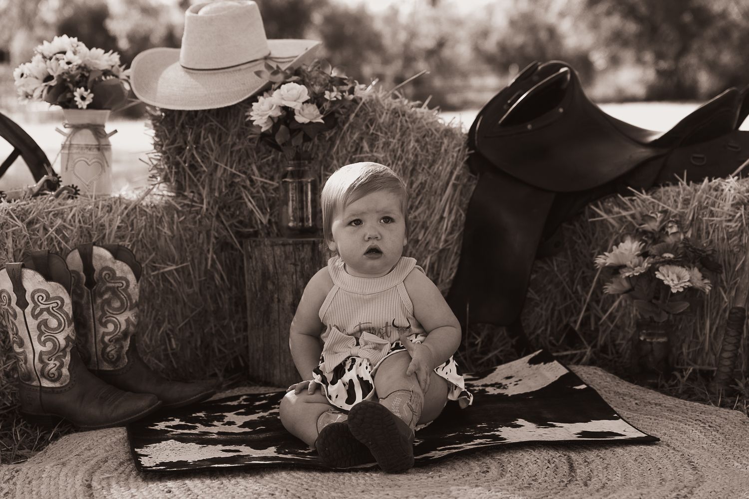 Girl sitting on cowhide mat at cowgirl cake smash professional photo shoot