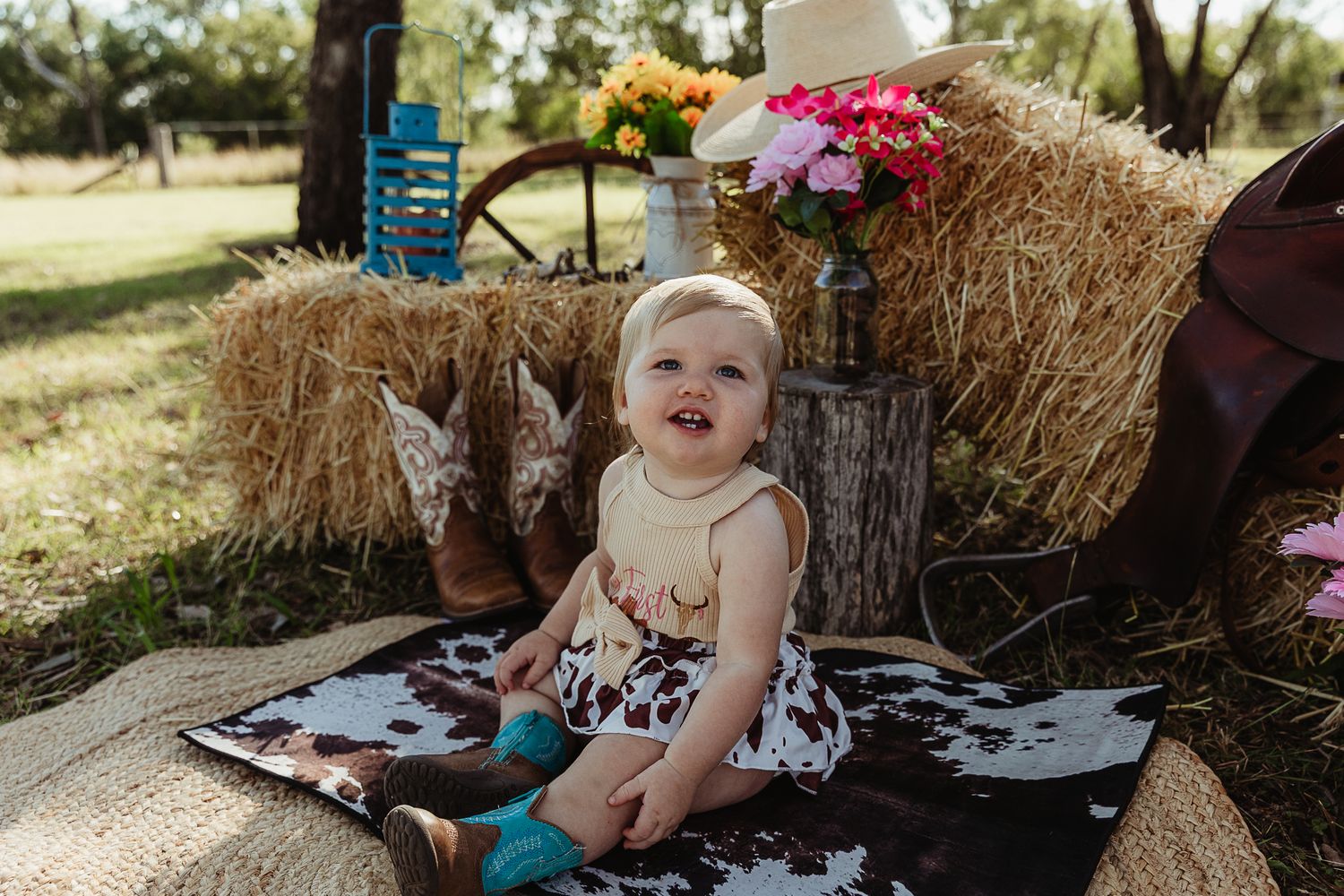 Girl sitting on cowhide mat at cowgirl cake smash professional photo shoot