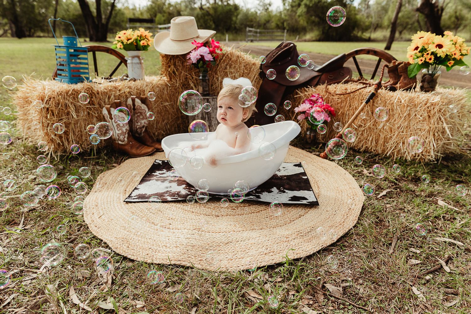 Girl sitting in bubble bath at cowgirl cake smash professional photo shoot