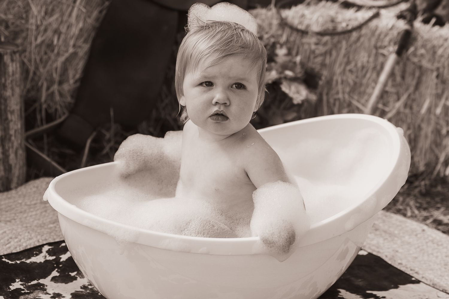 Girl sitting in bubble bath at cowgirl cake smash professional photo shoot