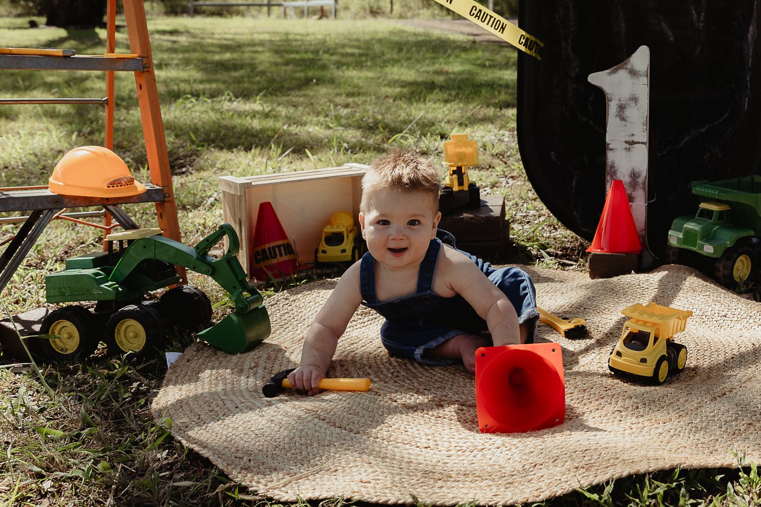 Boy playing with a tools at a construction cake smash photo shoot