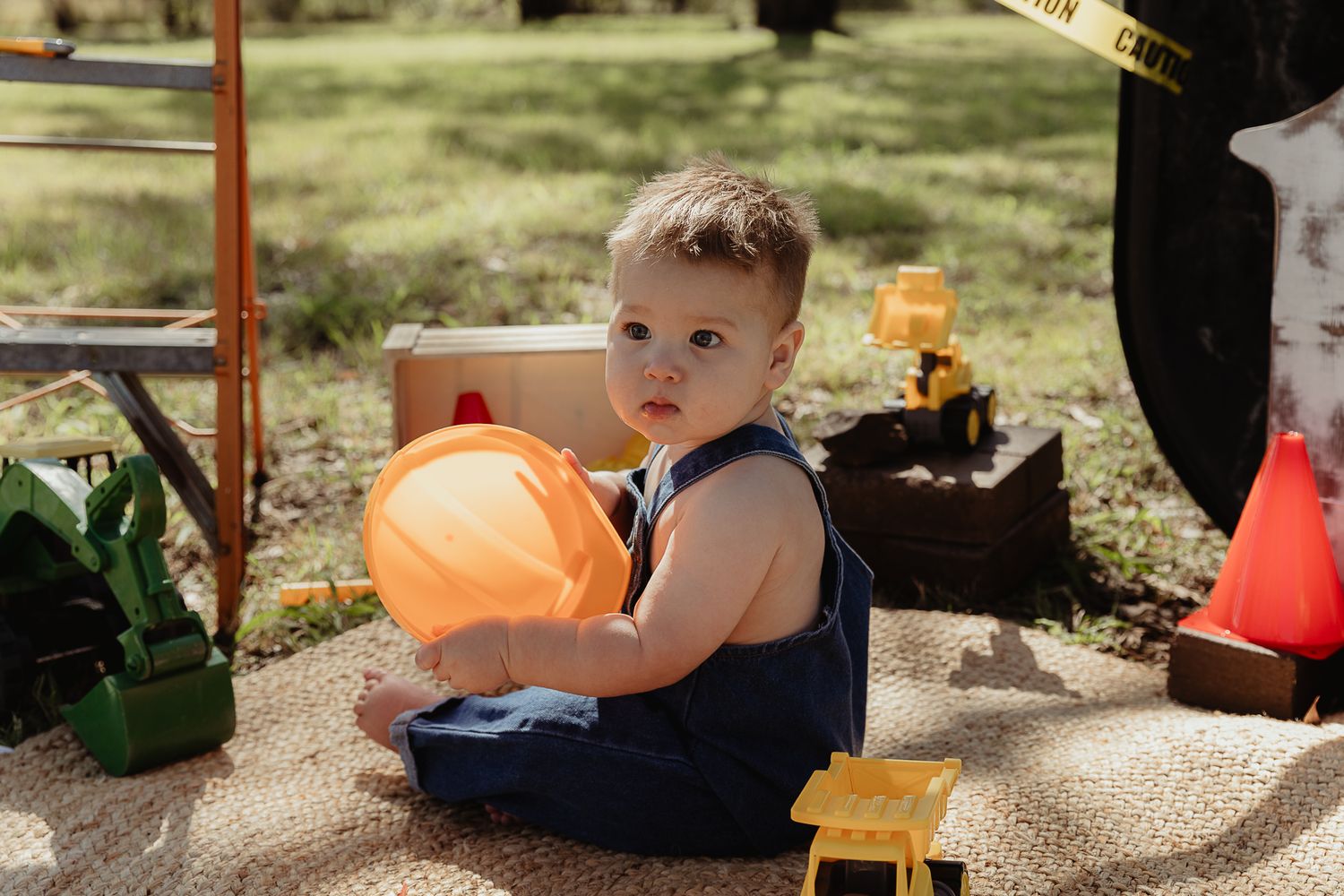 Boy playing with a hard hat at a construction cake smash photo shoot