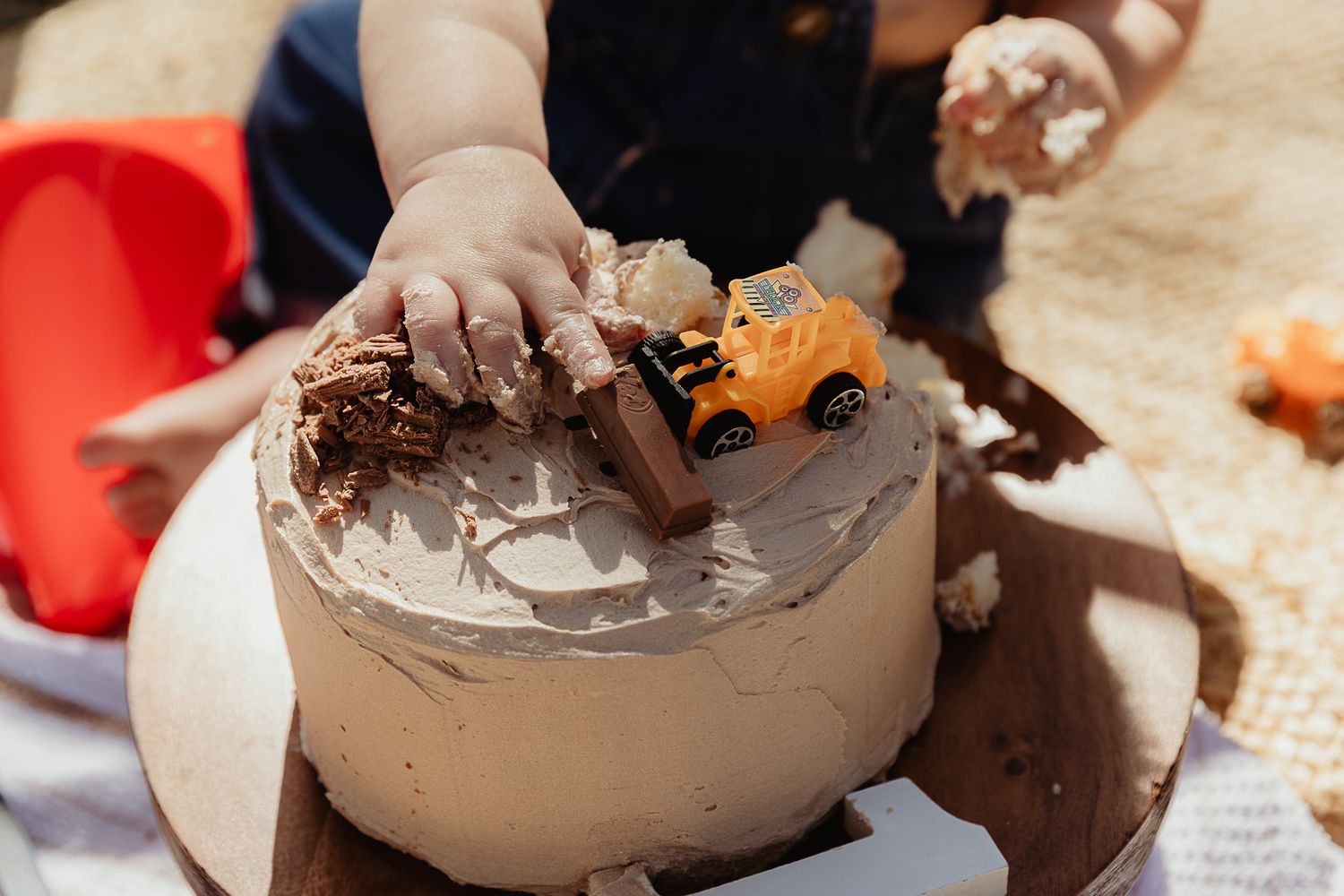 Boy getting hands messy with a cake at a construction cake smash photo shoot