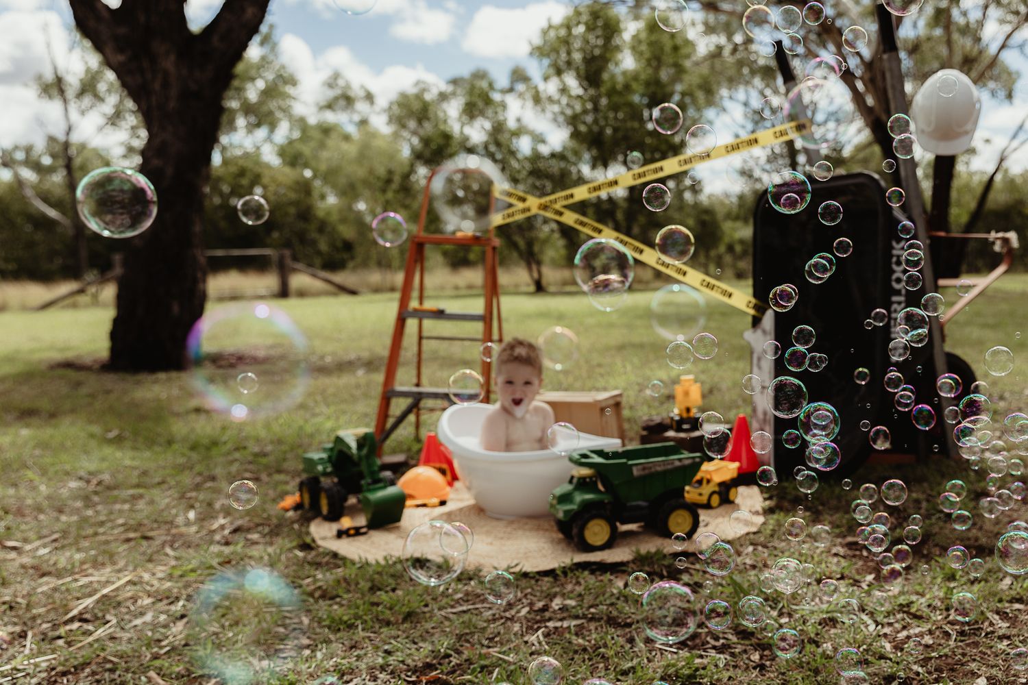 Boy in a bubble bath with bubbles at a construction cake smash photo shoot