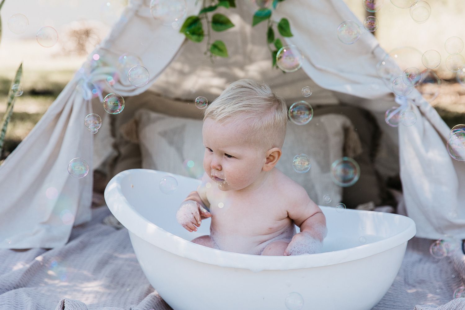 Baby boy sitting in a bubble bath at a "Wild One" professional cake smash photo shoot