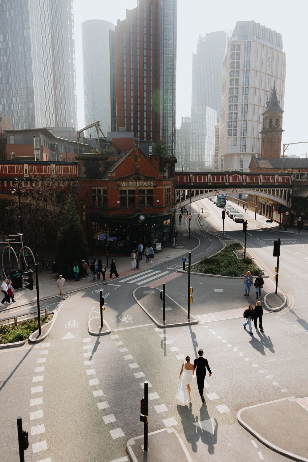 Aerial view of bride and groom crossing a busy urban intersection in Manchester city centre.